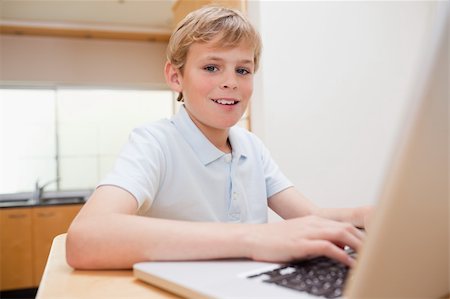 simsearch:400-04044137,k - Blond boy using a notebook in a kitchen Stock Photo - Budget Royalty-Free & Subscription, Code: 400-05749521