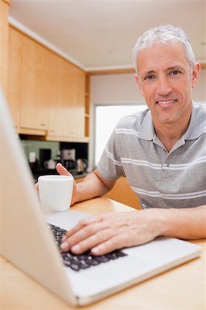 simsearch:400-05749531,k - Portrait of a man using a notebook while drinking tea in a kitchen Stock Photo - Budget Royalty-Free & Subscription, Code: 400-05749531