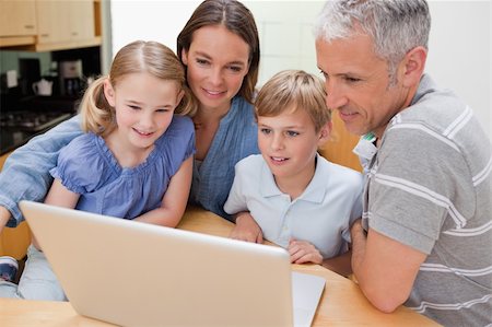 Lovely family using a laptop in their kitchen Stock Photo - Budget Royalty-Free & Subscription, Code: 400-05749547