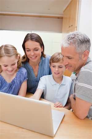 Portrait of a lovely family using a notebook in their kitchen Stock Photo - Budget Royalty-Free & Subscription, Code: 400-05749549