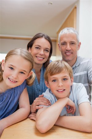 simsearch:400-05749624,k - Portrait of a cute family posing in a kitchen while looking at the camera Stock Photo - Budget Royalty-Free & Subscription, Code: 400-05749555