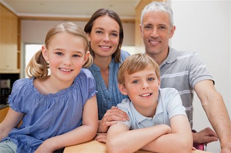 simsearch:400-05749624,k - Family posing in a kitchen while looking at the camera Stock Photo - Budget Royalty-Free & Subscription, Code: 400-05749553