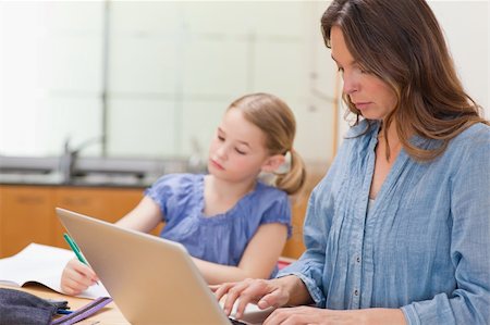 study online at home - Little girl doing her homework while her mother is using notebook in a kitchen Stock Photo - Budget Royalty-Free & Subscription, Code: 400-05749564