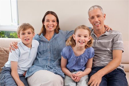 simsearch:400-05749645,k - Family sitting on a sofa while looking at the camera Stock Photo - Budget Royalty-Free & Subscription, Code: 400-05749595