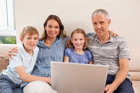 simsearch:400-05749624,k - Smiling family sitting on a sofa using a notebook in a living room Stock Photo - Budget Royalty-Free & Subscription, Code: 400-05749598
