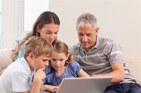 simsearch:400-05749624,k - Happy family sitting on a sofa using a notebook in a living room Stock Photo - Budget Royalty-Free & Subscription, Code: 400-05749599