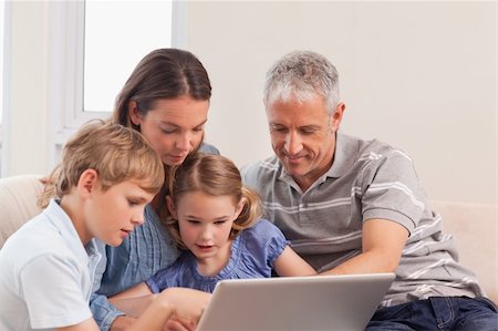 simsearch:400-05749624,k - Happy family sitting on a sofa using a laptop in a living room Stock Photo - Budget Royalty-Free & Subscription, Code: 400-05749600