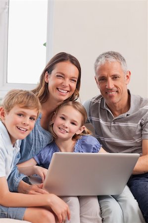simsearch:400-05749624,k - Portrait of a family sitting on a couch using a laptop in a living room Stock Photo - Budget Royalty-Free & Subscription, Code: 400-05749602