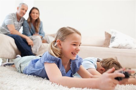 simsearch:400-05749624,k - Children playing video games with their parents on the background in a living room Stock Photo - Budget Royalty-Free & Subscription, Code: 400-05749629