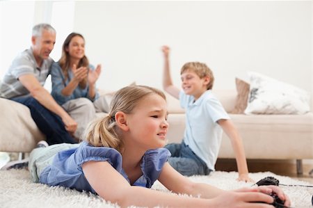 simsearch:400-05749624,k - Cute children playing video games with their parents on the background in the living room Stock Photo - Budget Royalty-Free & Subscription, Code: 400-05749630