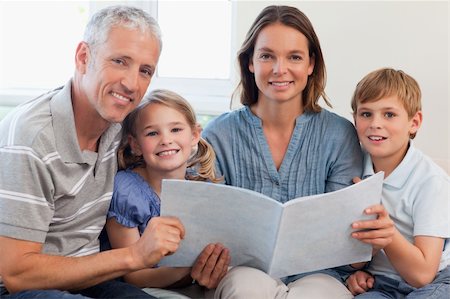 simsearch:400-05749644,k - Happy family reading a book together in a living room Stock Photo - Budget Royalty-Free & Subscription, Code: 400-05749642