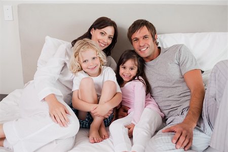 simsearch:400-05749479,k - Smiling family posing on a bed while looking at the camera Foto de stock - Royalty-Free Super Valor e Assinatura, Número: 400-05749777