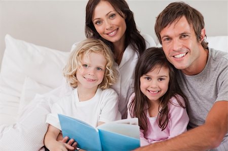 simsearch:400-05749479,k - Happy family reading a book in a bedroom Foto de stock - Royalty-Free Super Valor e Assinatura, Número: 400-05749783