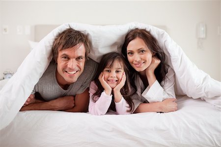 simsearch:400-04192409,k - Smiling parents lying under a duvet with their daughter in their bedroom Photographie de stock - Aubaine LD & Abonnement, Code: 400-05749797