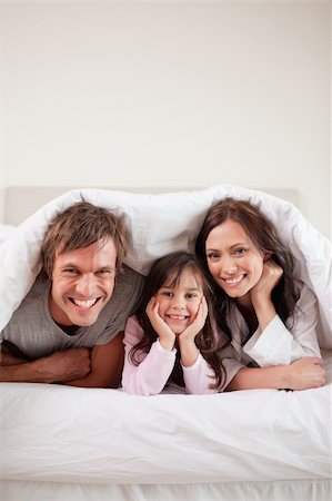 simsearch:400-04192438,k - Portrait of parents lying under a duvet with their daughter in their bedroom Photographie de stock - Aubaine LD & Abonnement, Code: 400-05749798