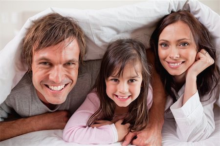 simsearch:400-04192409,k - Happy parents lying under a duvet with their daughter in their bedroom Photographie de stock - Aubaine LD & Abonnement, Code: 400-05749799