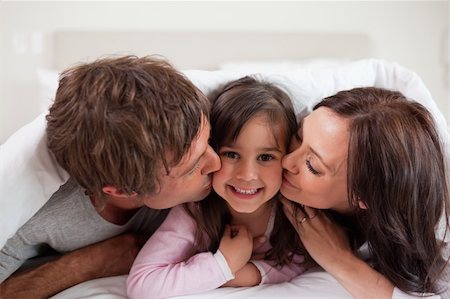 simsearch:400-04192409,k - Parents kissing their daughter while lying under a duvet Photographie de stock - Aubaine LD & Abonnement, Code: 400-05749801