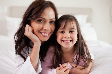 simsearch:400-05749479,k - Mother and her daughter lying on a bed while looking at the camera Foto de stock - Royalty-Free Super Valor e Assinatura, Número: 400-05749802