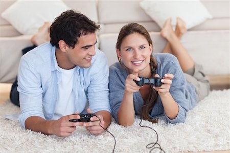 simsearch:400-05297936,k - Lovely couple playing video games while lying on a carpet Stock Photo - Budget Royalty-Free & Subscription, Code: 400-05740058