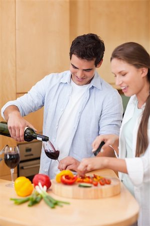 simsearch:400-04162443,k - Portrait of a cute man pouring a glass of wine while his wife is cooking in their kitchen Fotografie stock - Microstock e Abbonamento, Codice: 400-05740096