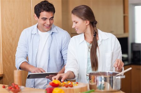 Charming couple using a tablet computer to cook in their kitchen Stock Photo - Budget Royalty-Free & Subscription, Code: 400-05740115