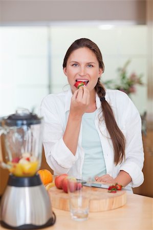 pretty women eating banana - Portrait of a woman eating a strawberry in her kitchen Photographie de stock - Aubaine LD & Abonnement, Code: 400-05740124