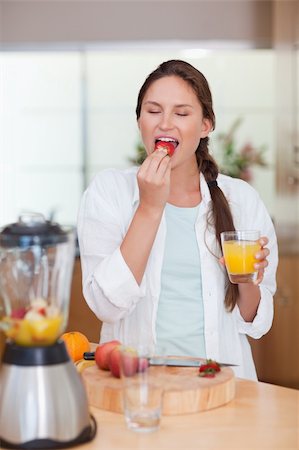 pretty women eating banana - Portrait of a cute woman eating a fresh strawberry in her kitchen Stock Photo - Budget Royalty-Free & Subscription, Code: 400-05740122