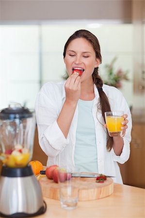 Portrait of a woman eating a fresh strawberry in her kitchen Stock Photo - Budget Royalty-Free & Subscription, Code: 400-05740123