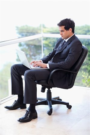 simsearch:400-07514126,k - Portrait of a businessman sitting on an armchair working with a laptop in his office Fotografie stock - Microstock e Abbonamento, Codice: 400-05740176