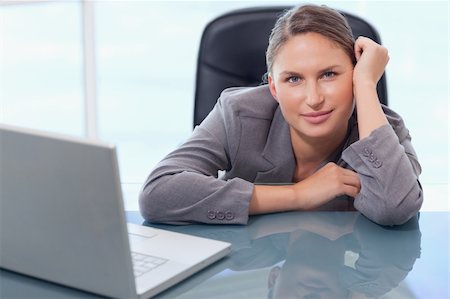 Young businesswoman leaning on her desk while looking at the camera Stock Photo - Budget Royalty-Free & Subscription, Code: 400-05740265