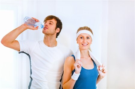 Male athlete drinking water from bottle and smiling girl in sportswear with towel Stock Photo - Budget Royalty-Free & Subscription, Code: 400-05740614