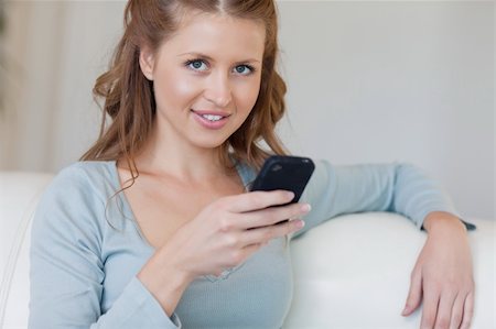 simsearch:400-05716936,k - Young woman on the couch typing on her smartphone Stock Photo - Budget Royalty-Free & Subscription, Code: 400-05740797