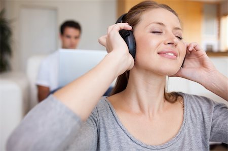 simsearch:400-05209351,k - Young woman listening to music with man sitting behind her on the sofa Stock Photo - Budget Royalty-Free & Subscription, Code: 400-05740925