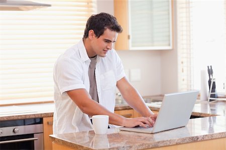 simsearch:400-05749531,k - Young man working on his laptop in the kitchen Stock Photo - Budget Royalty-Free & Subscription, Code: 400-05741083