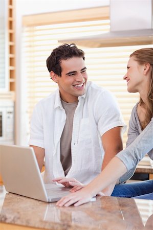 simsearch:400-05749531,k - Smiling young couple with laptop in the kitchen Stock Photo - Budget Royalty-Free & Subscription, Code: 400-05741105