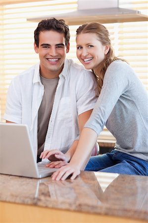 simsearch:400-05749531,k - Smiling young couple with notebook in the kitchen Stock Photo - Budget Royalty-Free & Subscription, Code: 400-05741107