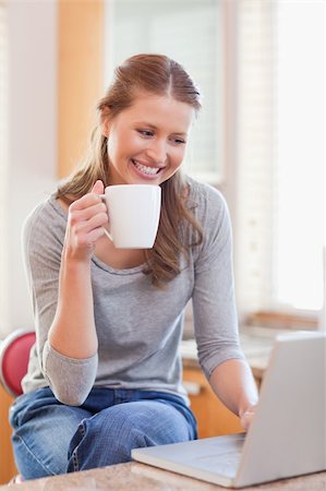 simsearch:400-05749531,k - Smiling young woman enjoying coffee while typing on her laptop Stock Photo - Budget Royalty-Free & Subscription, Code: 400-05741114