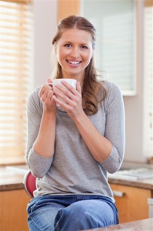 simsearch:400-05749531,k - Smiling young woman having a cup of coffee in the kitchen Stock Photo - Budget Royalty-Free & Subscription, Code: 400-05741115