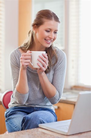 simsearch:400-05749531,k - Young woman having coffee while looking on her laptop Stock Photo - Budget Royalty-Free & Subscription, Code: 400-05741112