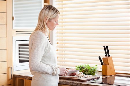 simsearch:400-05748090,k - Side view of young woman slicing ingredients for her salad Foto de stock - Super Valor sin royalties y Suscripción, Código: 400-05741480