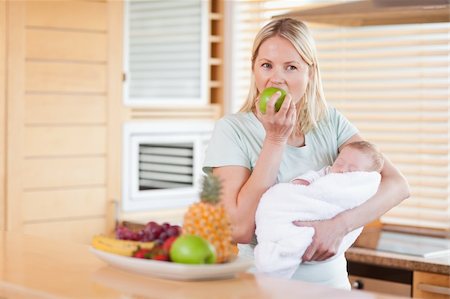 Young woman with baby on her arms eating an apple Stock Photo - Budget Royalty-Free & Subscription, Code: 400-05741509