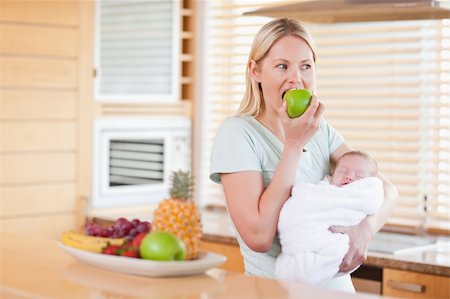 simsearch:400-05741507,k - Junge Frau beißen in Apfel mit Baby auf den Armen Stockbilder - Microstock & Abonnement, Bildnummer: 400-05741510