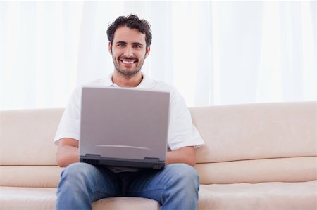 simsearch:400-05715528,k - Young man using a laptop in his living room Stock Photo - Budget Royalty-Free & Subscription, Code: 400-05741524