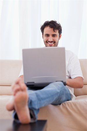 feet sofa comfort - Portrait of a man using a notebook in his living room Stock Photo - Budget Royalty-Free & Subscription, Code: 400-05741533