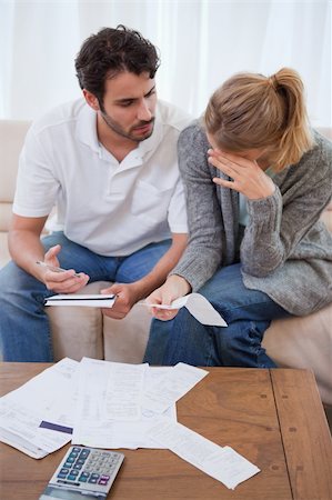 Portrait of a sad couple looking at their bills in their living room Stock Photo - Budget Royalty-Free & Subscription, Code: 400-05741558