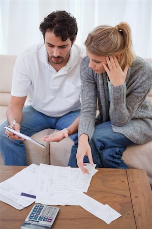 Portrait of a worried couple looking at their bills in their living room Stock Photo - Budget Royalty-Free & Subscription, Code: 400-05741559