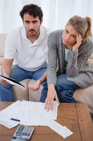 Portrait of a worried young couple looking at their bills in their living room Stock Photo - Budget Royalty-Free & Subscription, Code: 400-05741560
