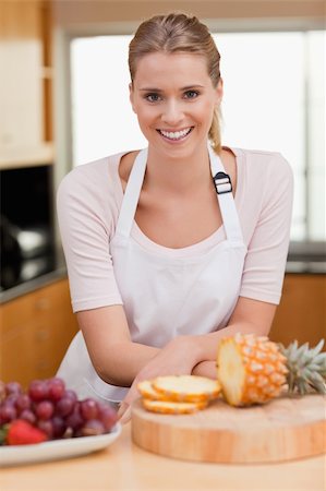 Portrait of a woman posing with a sliced pineapple in her kitchen Stock Photo - Budget Royalty-Free & Subscription, Code: 400-05741833