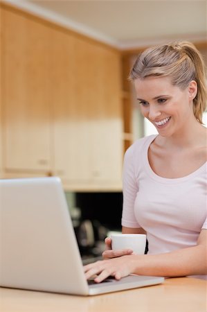 simsearch:400-05741872,k - Portrait of a woman using a laptop while drinking tea in her kitchen Foto de stock - Super Valor sin royalties y Suscripción, Código: 400-05741887