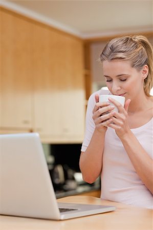 simsearch:400-05741872,k - Portrait of a young woman using a laptop while drinking tea in her kitchen Stockbilder - Microstock & Abonnement, Bildnummer: 400-05741890
